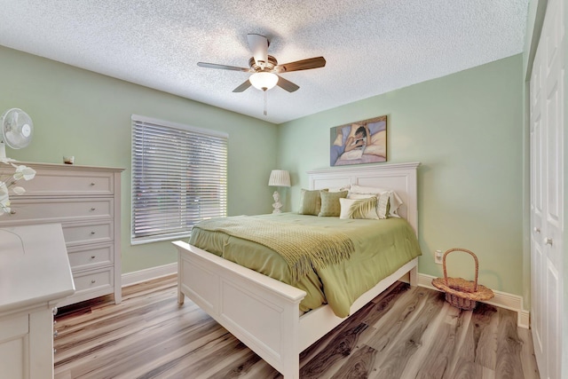 bedroom featuring a textured ceiling, ceiling fan, light wood-type flooring, and baseboards