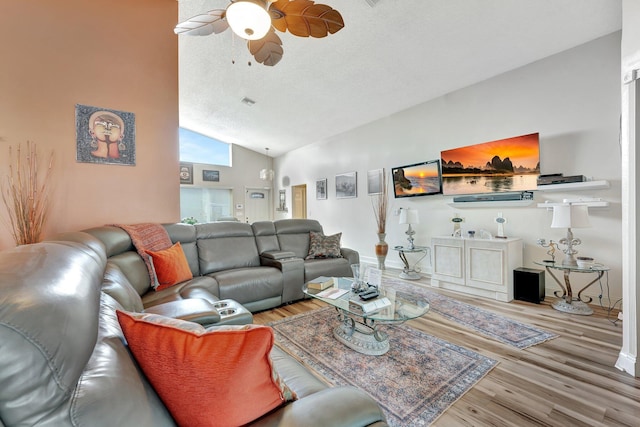 living area with a textured ceiling, wood finished floors, a ceiling fan, baseboards, and vaulted ceiling