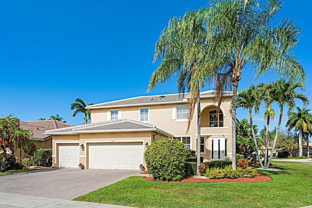 view of front of property with stucco siding, a front lawn, decorative driveway, a garage, and a tiled roof