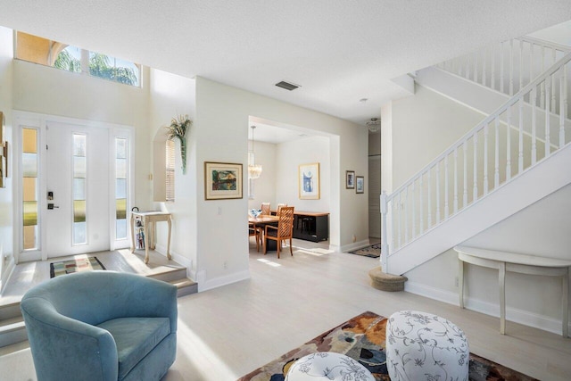 living room featuring visible vents, baseboards, wood finished floors, and stairs