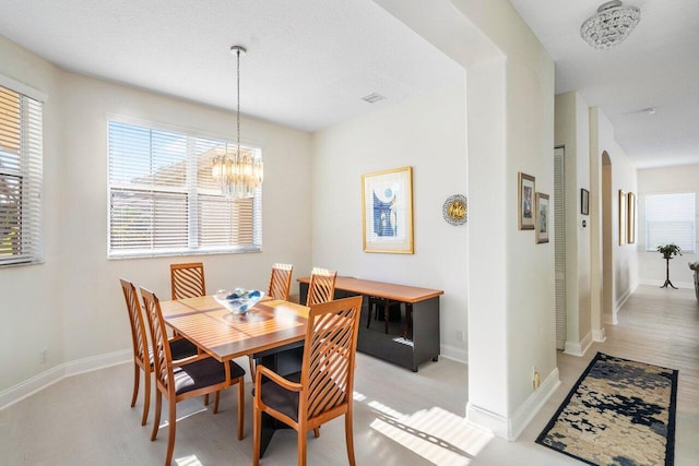 dining room with arched walkways, a notable chandelier, light wood-style floors, and baseboards