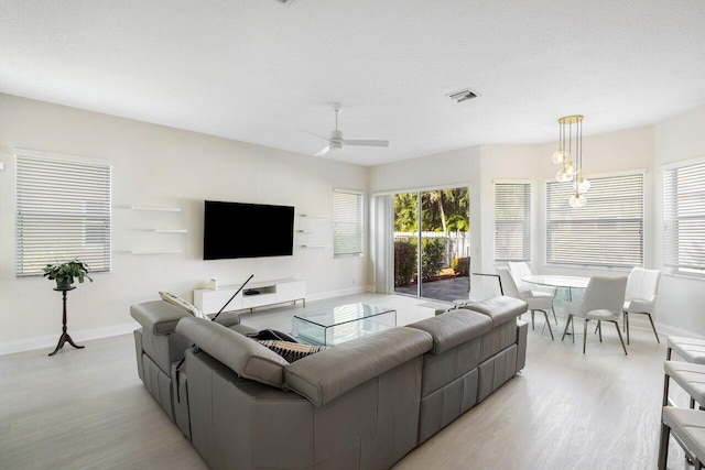 living area featuring a ceiling fan, visible vents, baseboards, and light wood-type flooring