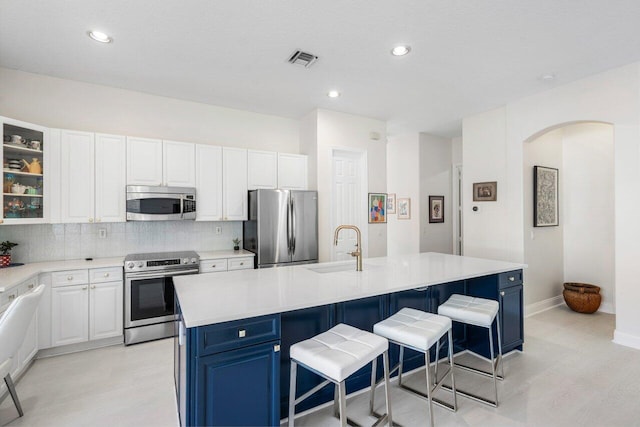 kitchen featuring backsplash, appliances with stainless steel finishes, white cabinets, and a sink