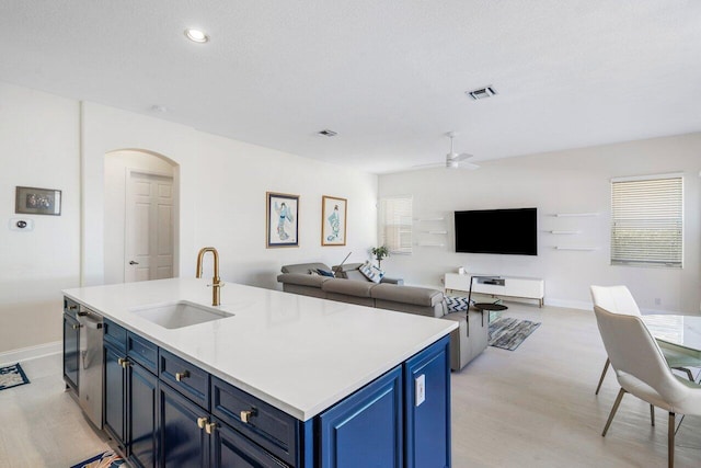 kitchen with visible vents, blue cabinetry, arched walkways, a sink, and light countertops