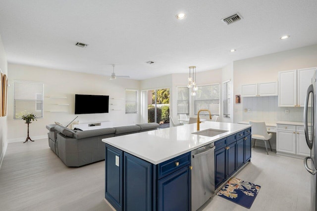 kitchen with visible vents, an island with sink, a sink, blue cabinetry, and stainless steel dishwasher