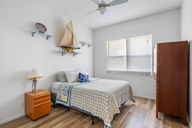 bedroom with ceiling fan, baseboards, and wood finished floors