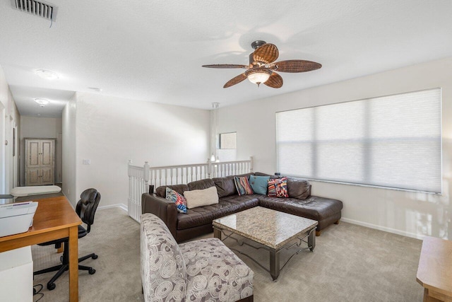 living room with visible vents, baseboards, ceiling fan, light colored carpet, and a textured ceiling