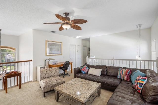 living room featuring visible vents, a ceiling fan, a textured ceiling, baseboards, and light colored carpet