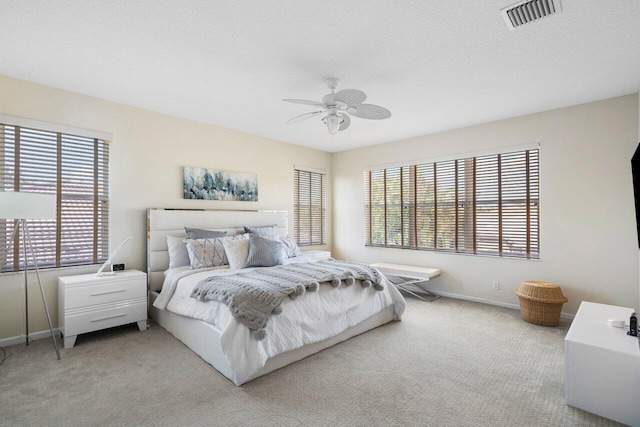 bedroom with visible vents, baseboards, carpet, a textured ceiling, and a ceiling fan