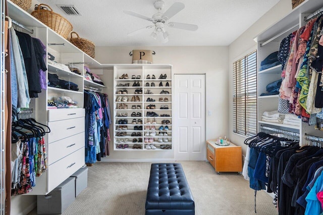 spacious closet featuring visible vents, carpet floors, and a ceiling fan