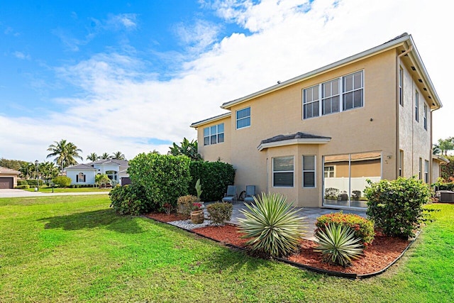 back of property with stucco siding, a patio, and a yard