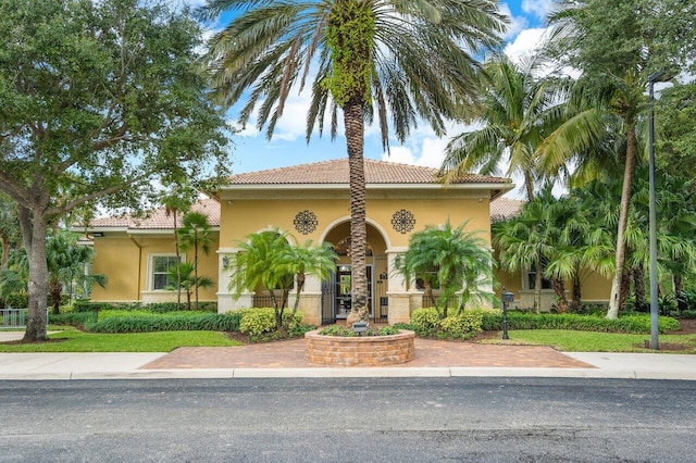 mediterranean / spanish house featuring stucco siding and a tile roof