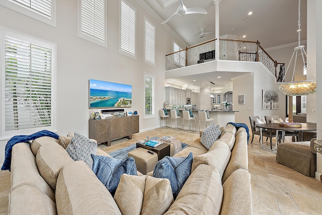 living room with ornamental molding, stone tile flooring, a towering ceiling, and baseboards