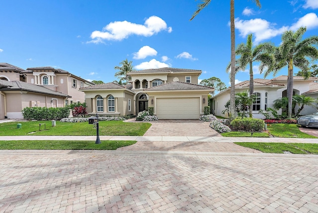 mediterranean / spanish home with a garage, a front lawn, decorative driveway, and stucco siding