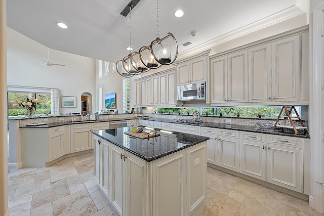 kitchen featuring stone tile floors, arched walkways, a kitchen island, a peninsula, and stainless steel appliances