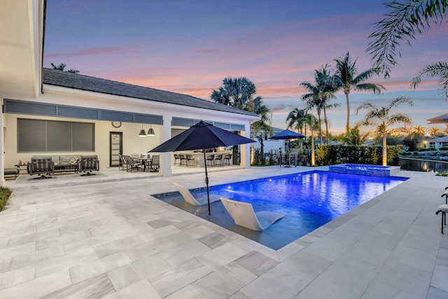 pool at dusk featuring a patio area, a pool with connected hot tub, and outdoor dining area