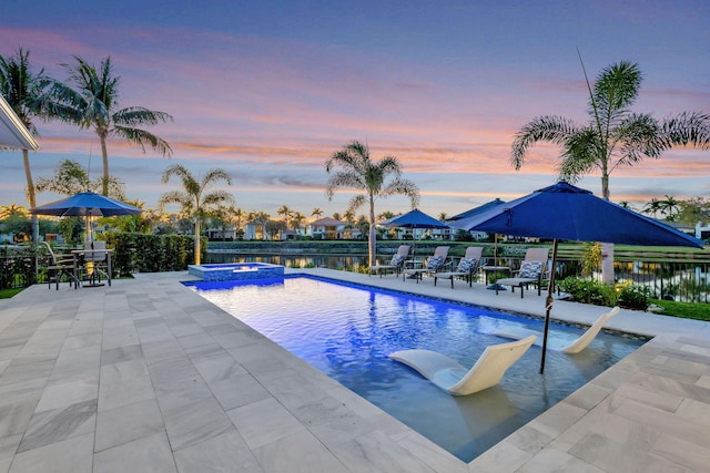 pool at dusk with a patio, fence, and a pool with connected hot tub