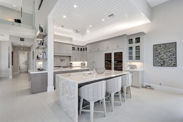 kitchen featuring decorative backsplash, wooden ceiling, a spacious island, a kitchen breakfast bar, and gray cabinetry