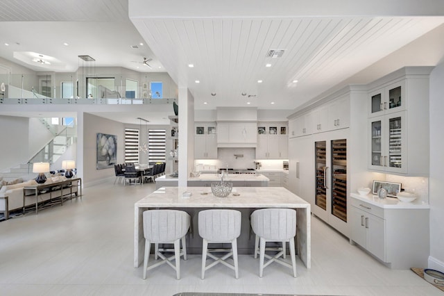 kitchen with wine cooler, visible vents, backsplash, open floor plan, and a large island with sink