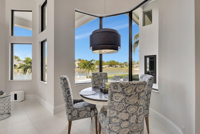 dining room featuring a high ceiling, baseboards, a wealth of natural light, and tile patterned floors