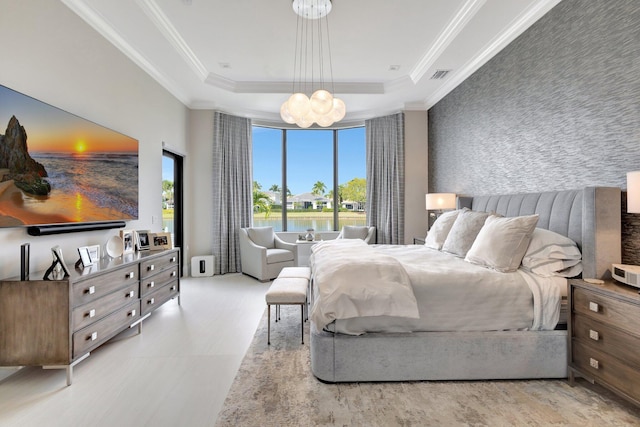 bedroom with ornamental molding, a tray ceiling, an accent wall, and visible vents