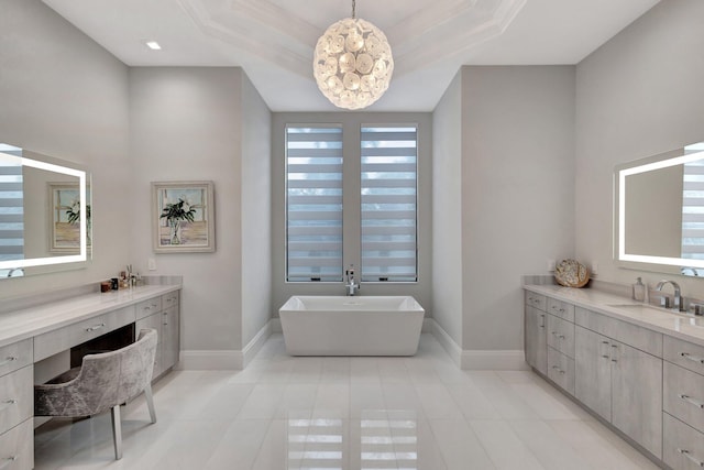 full bathroom featuring a freestanding tub, a raised ceiling, vanity, and baseboards