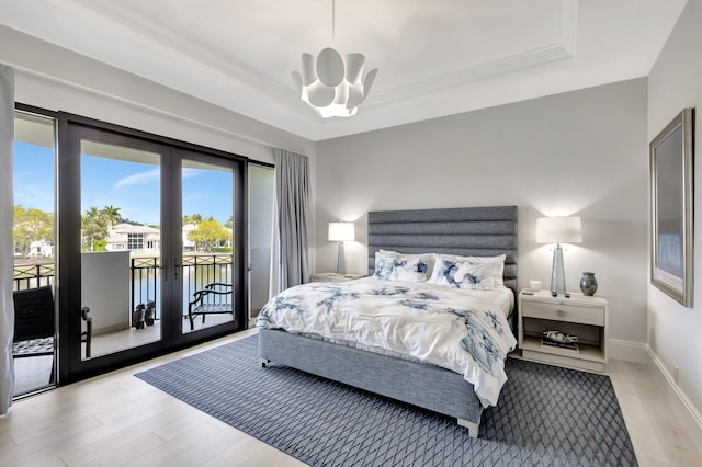 bedroom with french doors, a raised ceiling, light wood-style flooring, access to outside, and baseboards