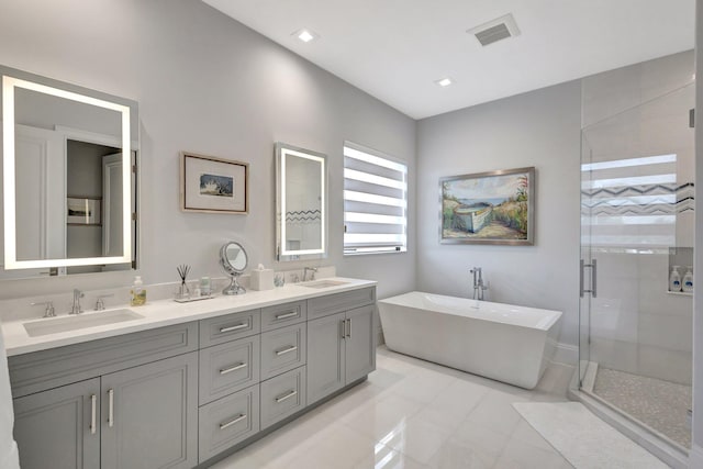 bathroom with double vanity, a shower stall, visible vents, and a sink