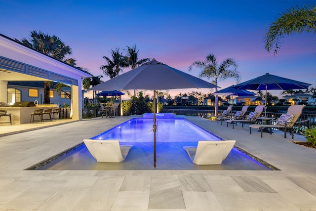 pool at dusk featuring outdoor dry bar, a patio area, and a fenced in pool