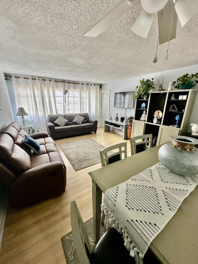 living room with ceiling fan, a textured ceiling, and wood finished floors