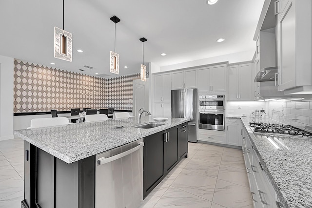 kitchen with recessed lighting, stainless steel appliances, a sink, marble finish floor, and a center island with sink