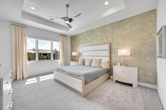 bedroom with carpet floors, visible vents, a tray ceiling, and baseboards