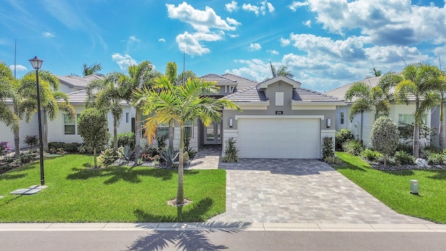 view of front of property with an attached garage, a tile roof, decorative driveway, stucco siding, and a front yard