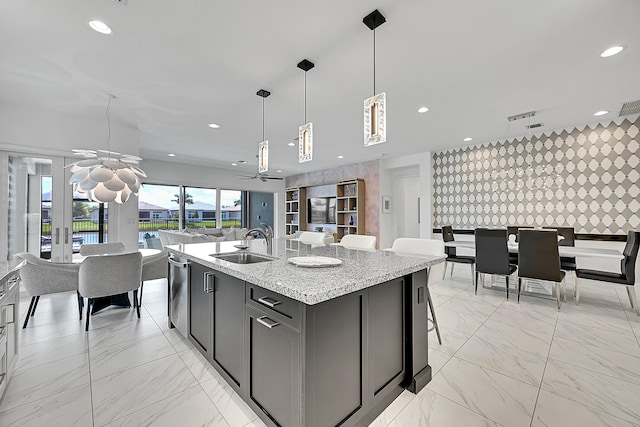 kitchen featuring pendant lighting, marble finish floor, recessed lighting, open floor plan, and a sink