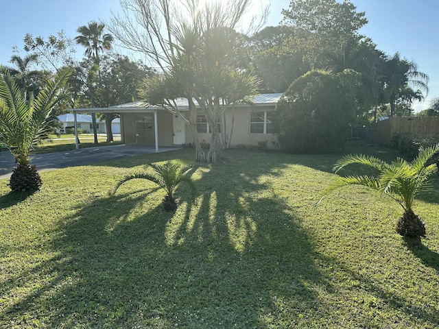 view of yard featuring a carport, concrete driveway, and fence