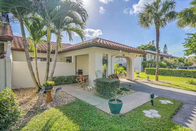 exterior space with a tile roof, fence, a lawn, and stucco siding