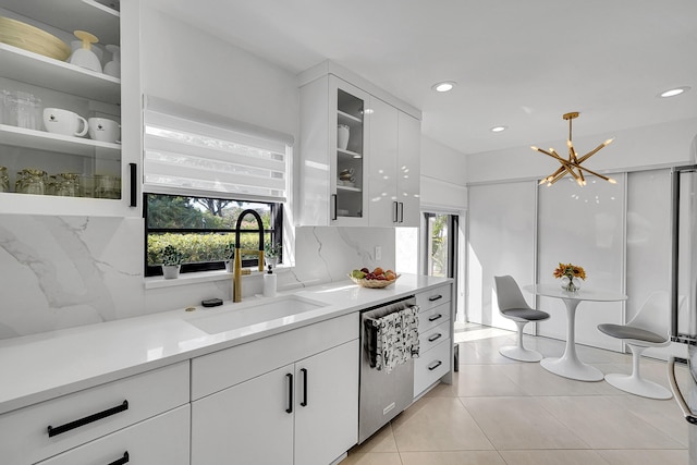 kitchen featuring a sink, white cabinetry, light countertops, stainless steel dishwasher, and backsplash