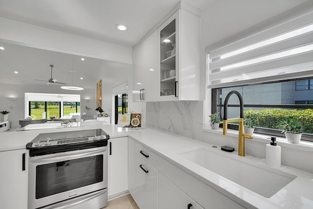 kitchen featuring light countertops, electric range, glass insert cabinets, white cabinetry, and a sink