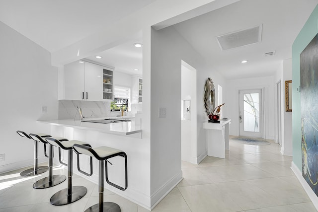 kitchen with a breakfast bar, light countertops, visible vents, decorative backsplash, and light tile patterned flooring