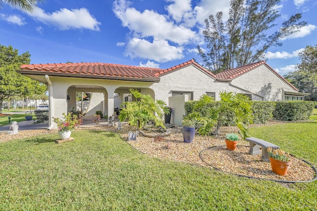 rear view of house with a tiled roof, a lawn, and stucco siding