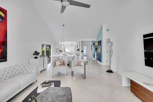 living room with light tile patterned floors, ceiling fan, high vaulted ceiling, and baseboards