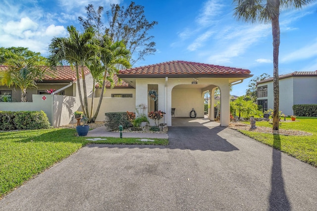 mediterranean / spanish home featuring aphalt driveway, fence, a tiled roof, stucco siding, and a front lawn