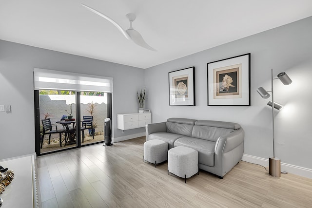 living room with light wood finished floors, baseboards, and a ceiling fan