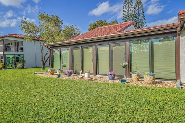 back of property featuring a tile roof and a yard