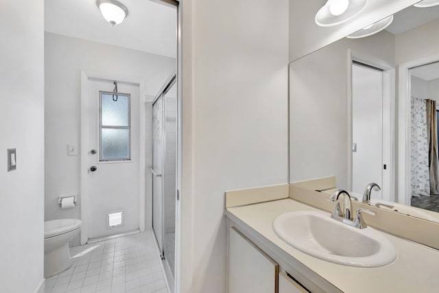 bathroom with a stall shower, vanity, toilet, and tile patterned floors