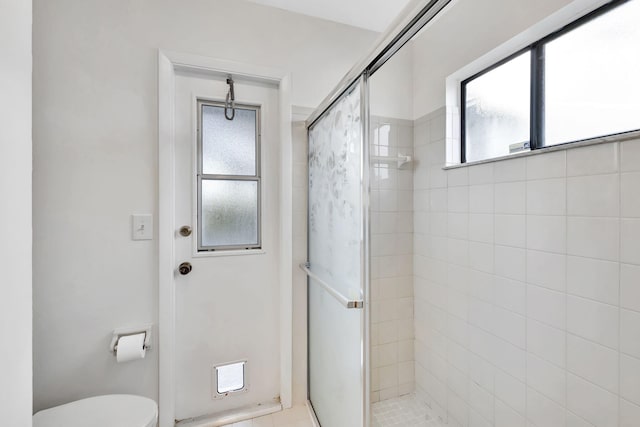 bathroom with toilet, a stall shower, and a healthy amount of sunlight