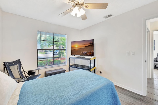 bedroom featuring ceiling fan, wood finished floors, visible vents, and baseboards