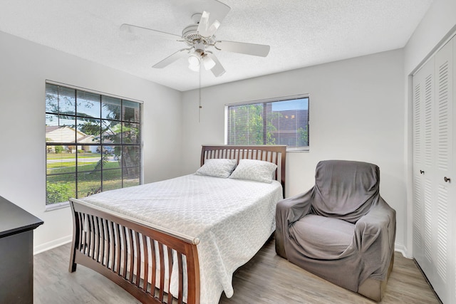 bedroom with baseboards, ceiling fan, wood finished floors, a textured ceiling, and a closet