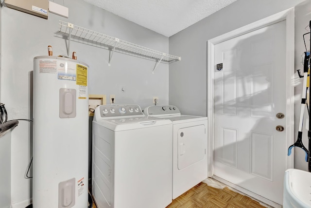 laundry room with laundry area, electric water heater, a textured ceiling, and washing machine and clothes dryer