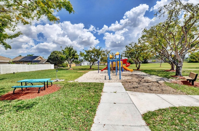 community play area featuring a lawn and fence